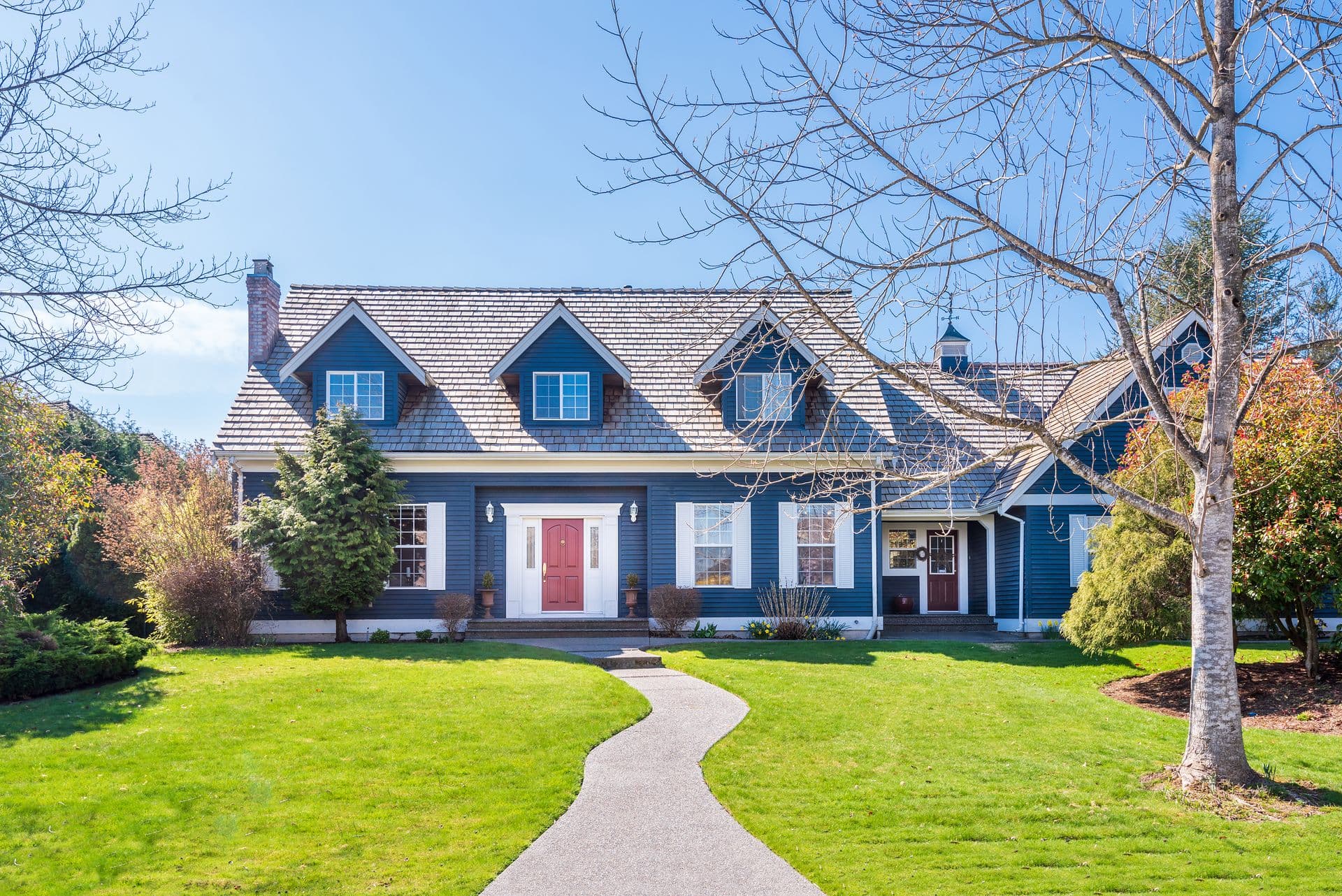 Beautiful exterior of newly built luxury home. Yard with green grass and walkway lead to front entrance.